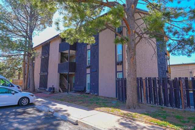 view of building exterior with fence and stairs