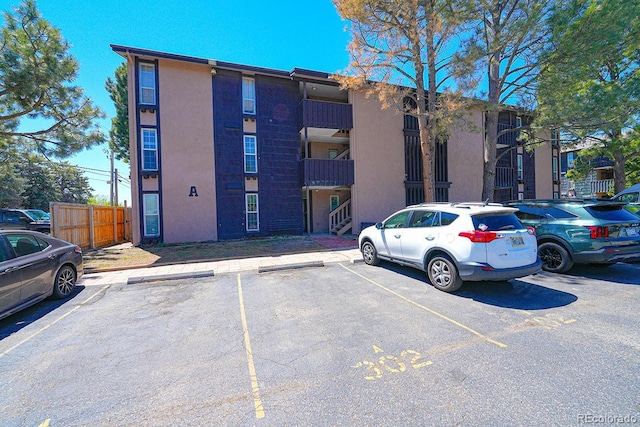 view of building exterior with fence and uncovered parking