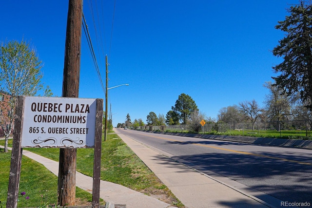 view of road featuring traffic signs, sidewalks, and street lights