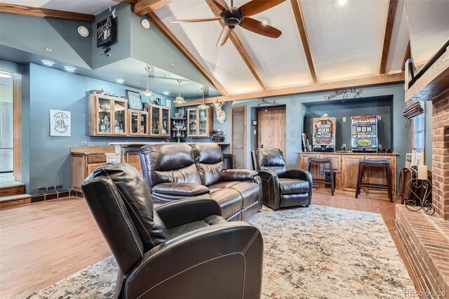 living room with beamed ceiling, ceiling fan, bar area, and light wood-type flooring