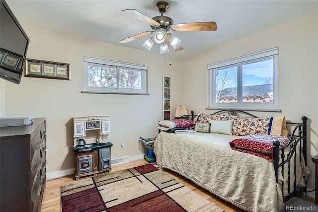 bedroom featuring ceiling fan, multiple windows, and light hardwood / wood-style flooring