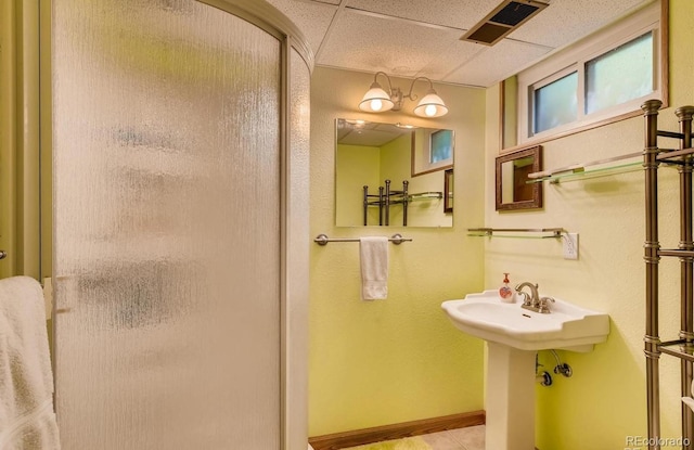 bathroom with tile patterned flooring, a drop ceiling, and an enclosed shower