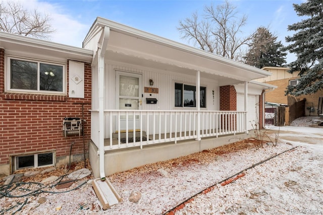 ranch-style home featuring an attached garage, a porch, and brick siding