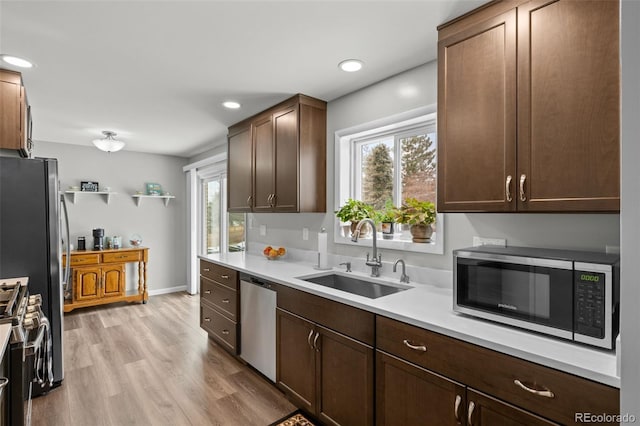 kitchen featuring appliances with stainless steel finishes, light countertops, light wood-type flooring, a sink, and recessed lighting