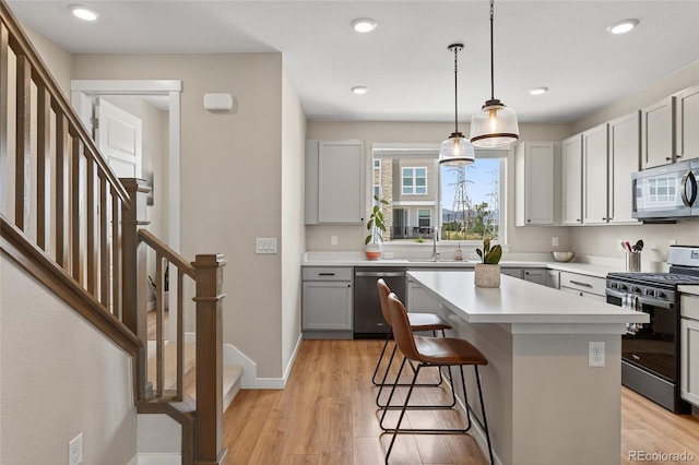 5396 Quail St, Wheat Ridge, CO 80033 - kitchen with stainless steel appliances, light wood finished floors, light countertops, a breakfast bar area, and recessed lighting