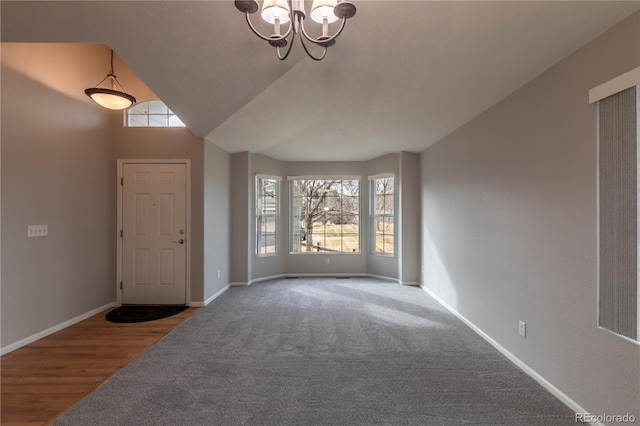 entrance foyer featuring carpet flooring, an inviting chandelier, and lofted ceiling