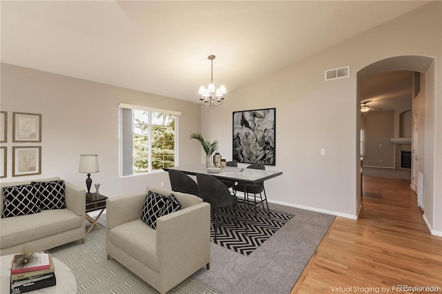 living room with hardwood / wood-style floors, ceiling fan with notable chandelier, and lofted ceiling