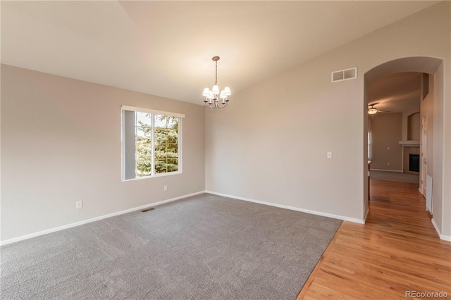 empty room featuring ceiling fan with notable chandelier and lofted ceiling