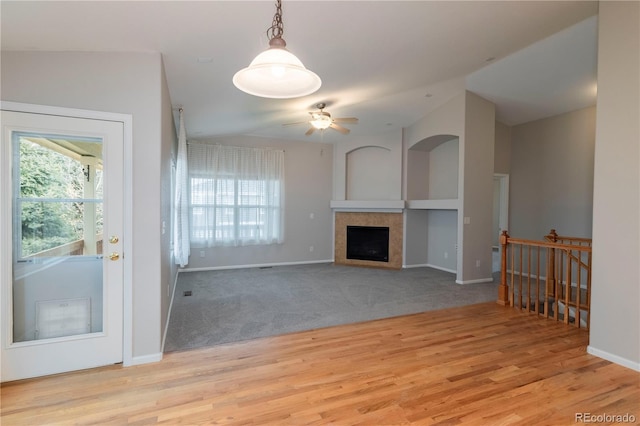 unfurnished living room with ceiling fan, a fireplace, light carpet, and vaulted ceiling