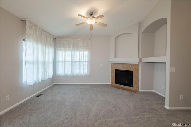 unfurnished living room with ceiling fan, vaulted ceiling, carpet floors, and a tiled fireplace