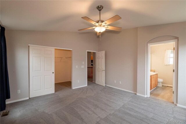 unfurnished bedroom featuring ceiling fan, light carpet, connected bathroom, and a closet