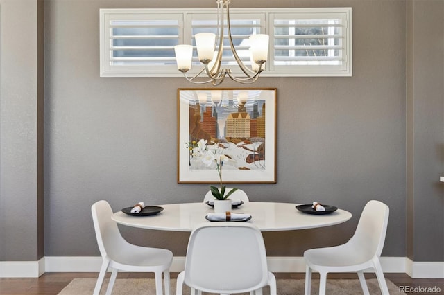 dining room with a chandelier, baseboards, and wood finished floors