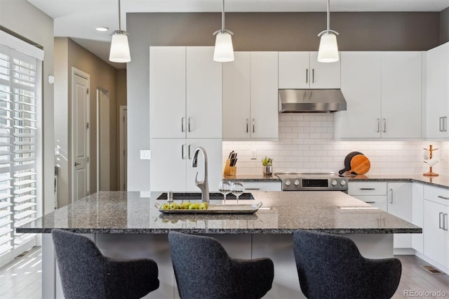 kitchen with pendant lighting, electric stove, decorative backsplash, and under cabinet range hood