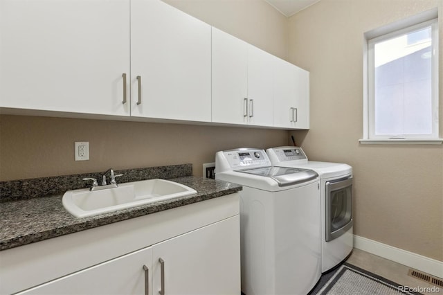 washroom featuring washing machine and clothes dryer, cabinet space, visible vents, a sink, and baseboards