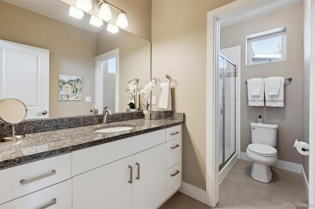 bathroom featuring vanity, a shower stall, toilet, and baseboards