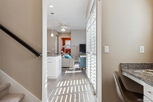 foyer entrance with ceiling fan, a textured wall, stairway, and built in study area