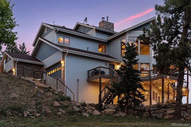 back house at dusk featuring a garage and a balcony