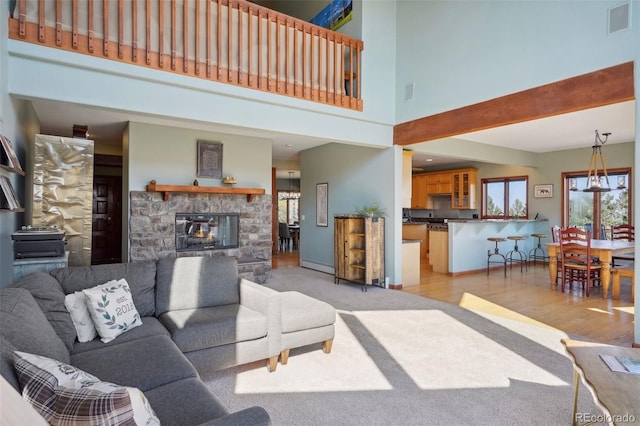 living room featuring a fireplace, a high ceiling, and light hardwood / wood-style floors