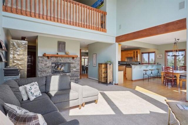 12421 High Country Trl, Littleton, CO 80127 - living room featuring a towering ceiling, a fireplace, light wood-style floors, and baseboards