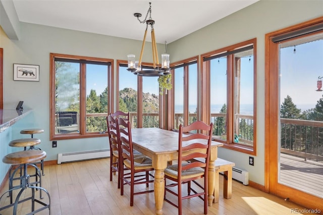 dining room with an inviting chandelier, light hardwood / wood-style floors, and a baseboard radiator