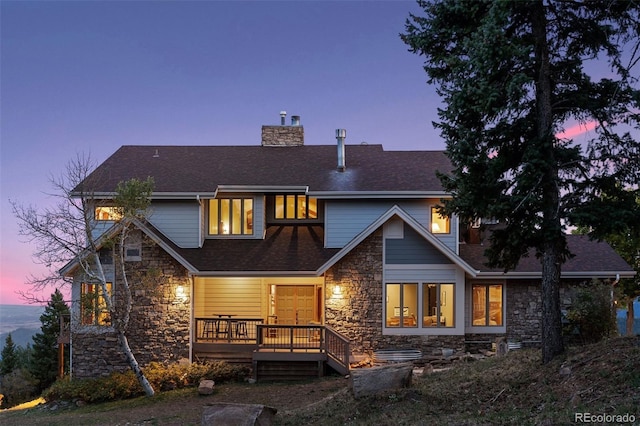 back house at dusk featuring a wooden deck