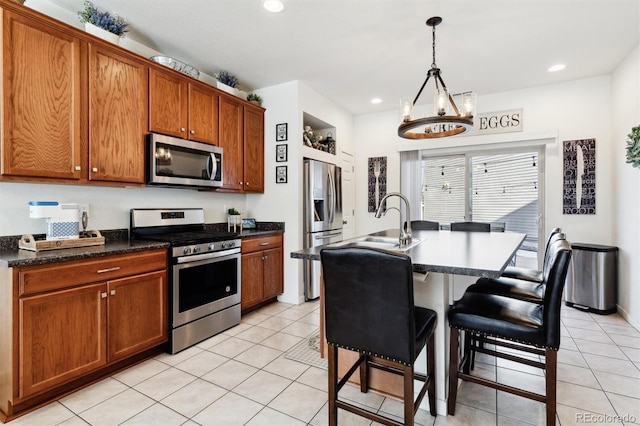 kitchen with sink, decorative light fixtures, an island with sink, a breakfast bar area, and appliances with stainless steel finishes