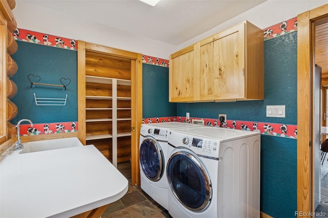 washroom with cabinet space, stone finish floor, washing machine and dryer, and a sink