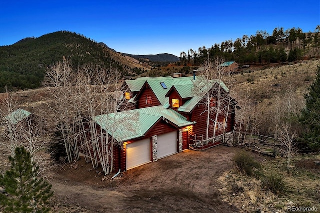 view of side of property with a garage, fence, metal roof, a mountain view, and driveway