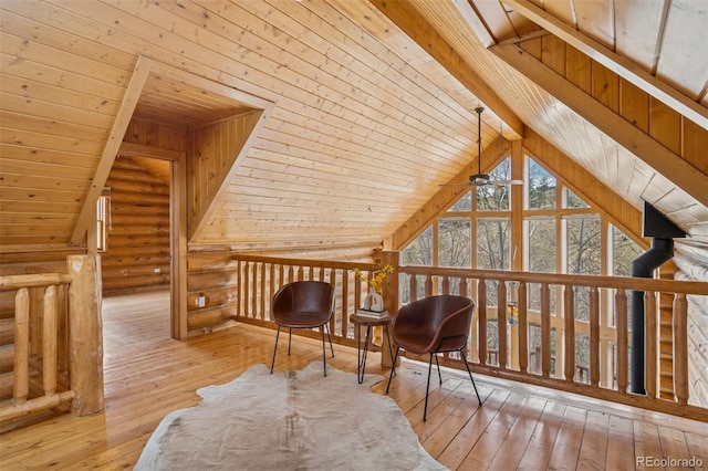 additional living space with a ceiling fan, wooden ceiling, rustic walls, lofted ceiling with beams, and hardwood / wood-style floors