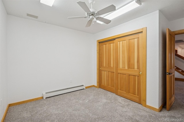 unfurnished bedroom with a closet, a ceiling fan, baseboards, baseboard heating, and carpet flooring