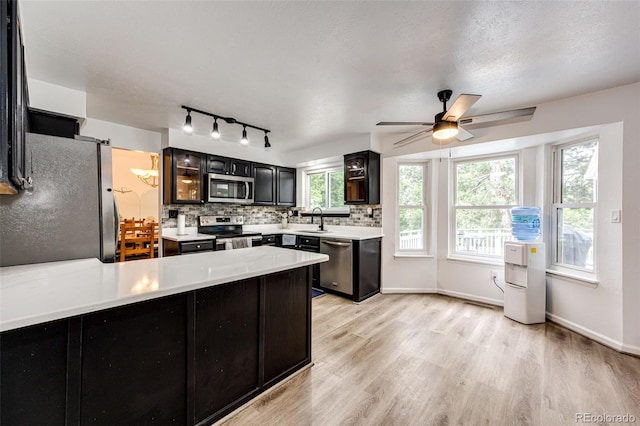 7840 W Portland Ave, Littleton, CO 80128 - kitchen with stainless steel appliances, light wood-style flooring, a peninsula, backsplash, and light countertops