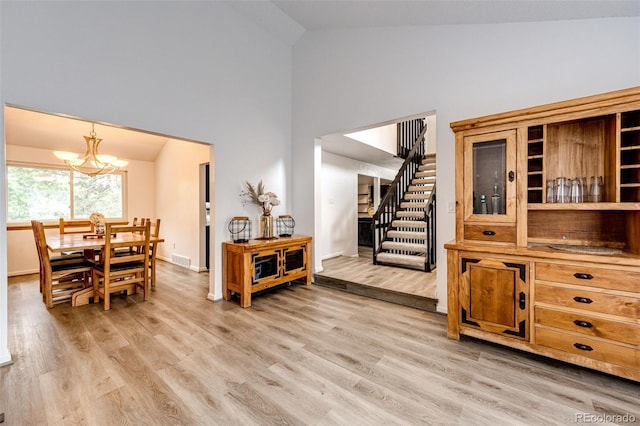7840 W Portland Ave, Littleton, CO 80128 - dining area with high vaulted ceiling, a chandelier, light wood finished floors, and stairway
