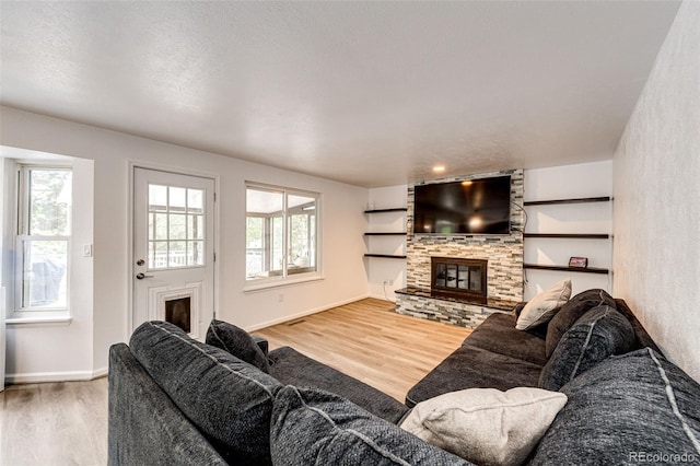 7840 W Portland Ave, Littleton, CO 80128 - living room featuring healthy amount of natural light, wood finished floors, and a stone fireplace