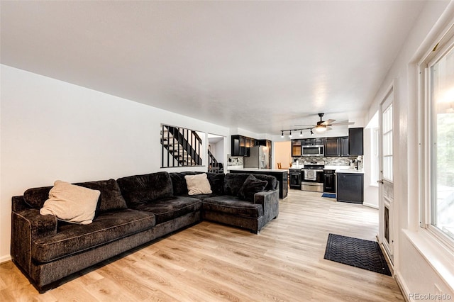 7840 W Portland Ave, Littleton, CO 80128 - living room with stairway, light wood-style floors, and a ceiling fan