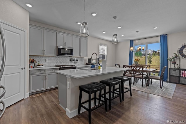 379 Silver Rock Trl, Castle Rock, CO 80104 - kitchen featuring stainless steel microwave, gray cabinets, dark wood finished floors, backsplash, and light countertops