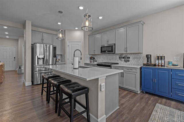379 Silver Rock Trl, Castle Rock, CO 80104 - kitchen featuring appliances with stainless steel finishes, dark wood-style floors, a breakfast bar, backsplash, and light countertops