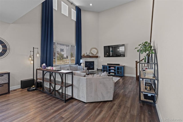 379 Silver Rock Trl, Castle Rock, CO 80104 - living room featuring a high ceiling, a glass covered fireplace, healthy amount of natural light, and dark wood finished floors