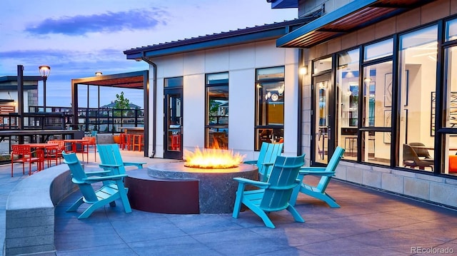 patio terrace at dusk featuring an outdoor fire pit