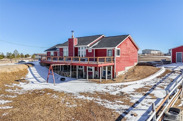 snow covered house with a deck and a chimney