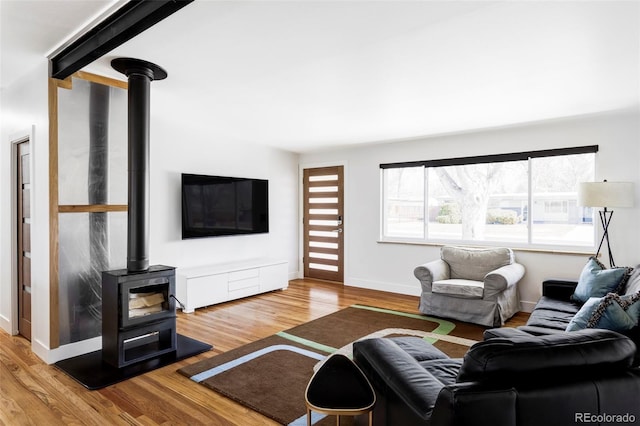 living area featuring a wood stove, baseboards, and wood finished floors