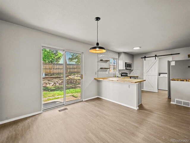 3535 Beechwood Ct, Colorado Springs, CO 80918 - kitchen with stainless steel appliances, a barn door, wood finished floors, and washer / dryer