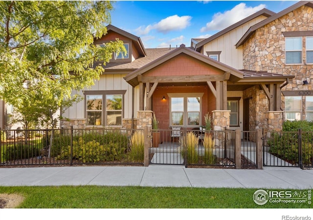 view of front of home featuring stone siding, a gate, board and batten siding, and a fenced front yard