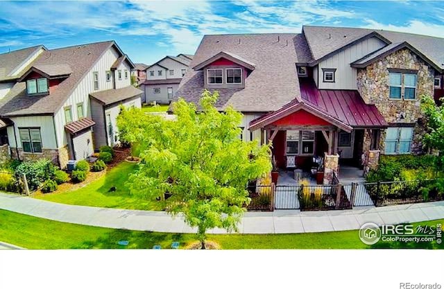 view of front facade featuring a standing seam roof, fence private yard, a patio area, a residential view, and metal roof