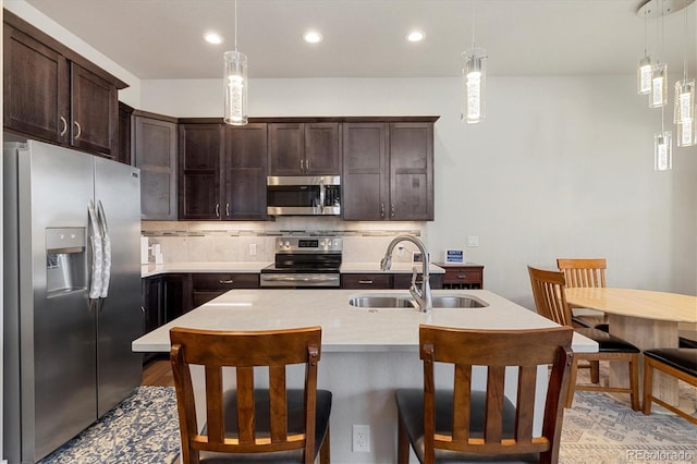 kitchen featuring decorative backsplash, dark brown cabinets, appliances with stainless steel finishes, and a sink