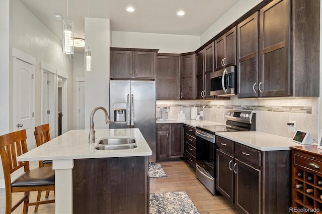 kitchen featuring a sink, appliances with stainless steel finishes, light countertops, decorative backsplash, and dark brown cabinets