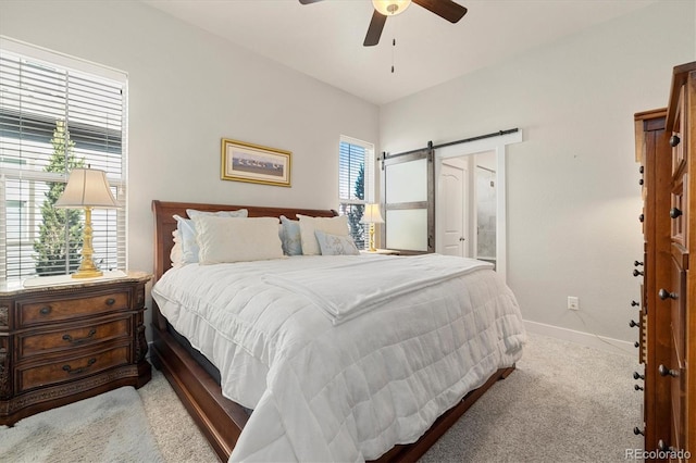 bedroom with connected bathroom, baseboards, a barn door, carpet floors, and a ceiling fan