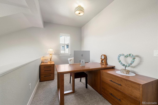 carpeted office space featuring baseboards and vaulted ceiling