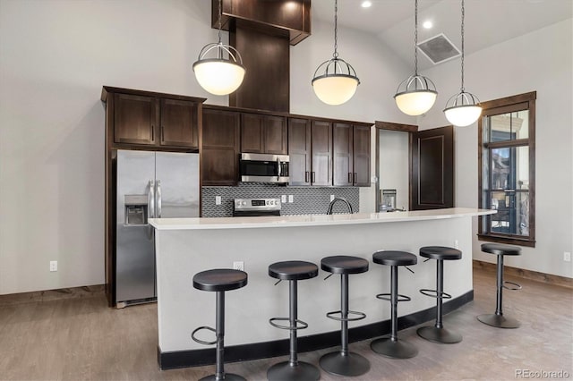 kitchen with dark brown cabinetry, backsplash, stainless steel appliances, and light countertops