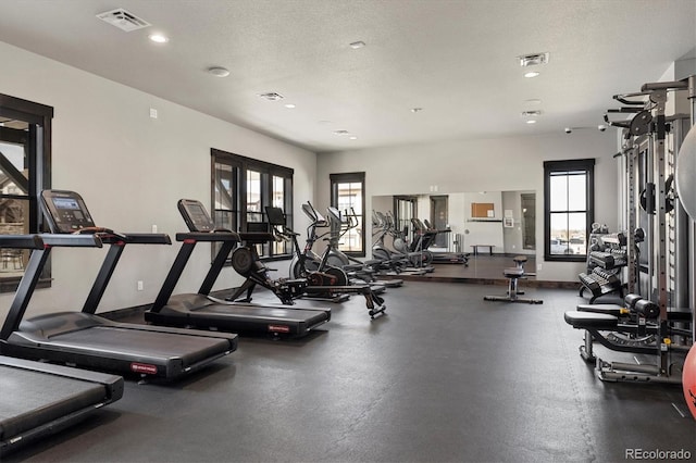 exercise room with visible vents, recessed lighting, a textured ceiling, and baseboards