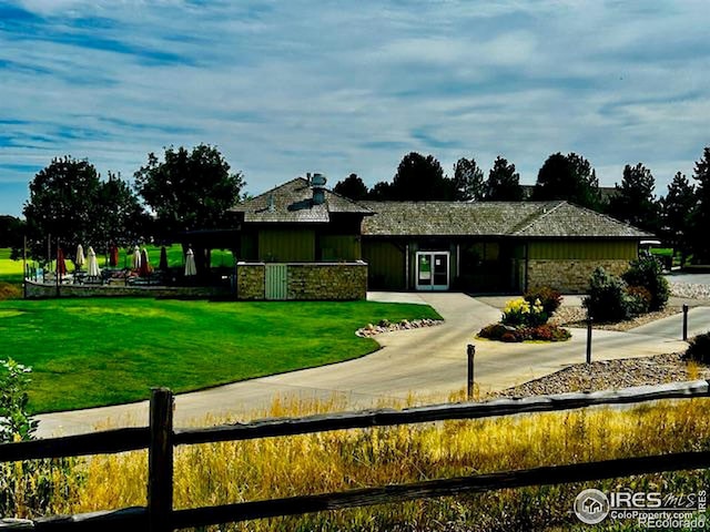 view of front of house with stone siding, a front yard, and fence